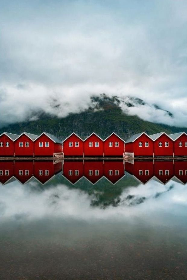Cabanes rouges de pêcheurs se reflétant dans un fjord